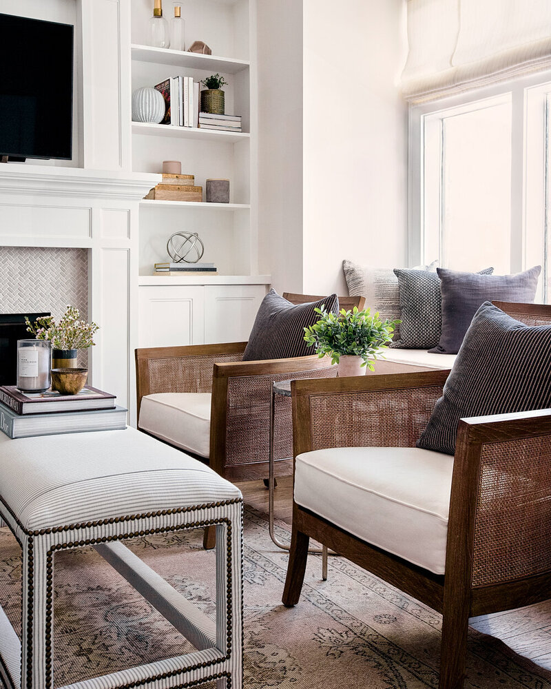 coastal living room with cane chairs vintage rug and striped upholstered ottoman